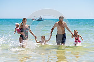 Group of happy children playing and splashing in the sea beach. Kids having fun outdoors. Summer vacation and healthy
