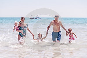 Group of happy children playing and splashing in the sea beach. Kids having fun outdoors. Summer vacation and healthy