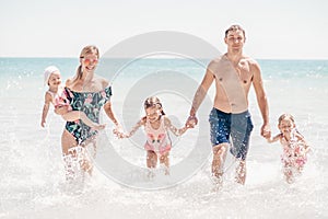 Group of happy children playing and splashing in the sea beach. Kids having fun outdoors. Summer vacation and healthy