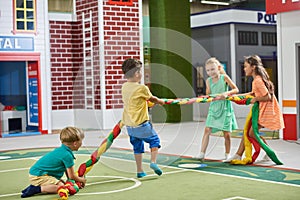 Group of happy children playing tug of war indoor.