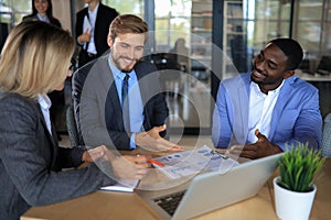 Group of happy diverse male and female business people in formal gathered around laptop computer in bright office.