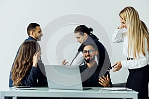 Group of happy diverse male and female business people in formal gathered around laptop computer in office