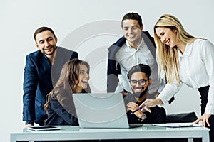 Group of happy diverse male and female business people in formal gathered around laptop computer in office