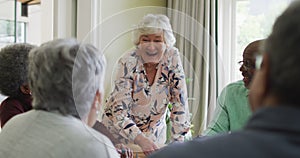 Group of happy diverse senior friends drinking coffee and doing puzzle at home