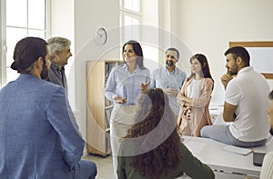 Group of happy employees having a meeting with a female team leader or business coach