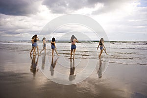 Group of happy and excited young women enjoying having fun on beautiful sunset beach in girlfriends summer holidays trip together