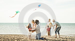 Group of happy families with parent and children playing with kite at beach vacation - Summer joy carefree concept with mixed