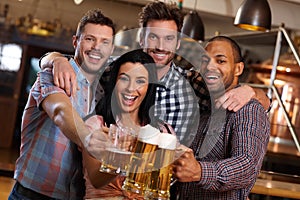 Group of happy friends clinking with beer in pub