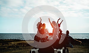 Group of happy friends doing excursion on desert in convertible 4x4 car - Young people having fun traveling together - Friendship