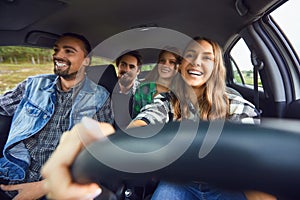 A group of happy friends are driving in a car.