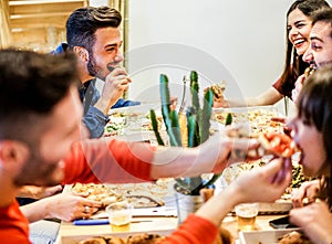 Group of happy friends eating home delivery pizza at home - Young trendy students having fun laughing together at dinner - Focus