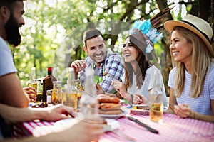 Group of happy friends eating and toasting at garden barbecue