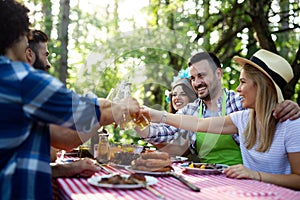 Group of happy friends eating and toasting at garden barbecue