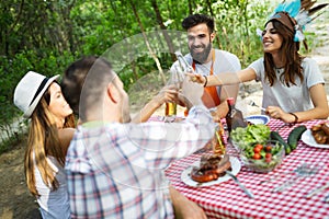 Group of happy friends eating and toasting at garden barbecue