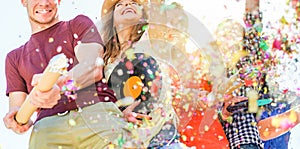 Group of happy friends enjoying party and throwing confetti - Young people having fun outdoor dancing and listening music at