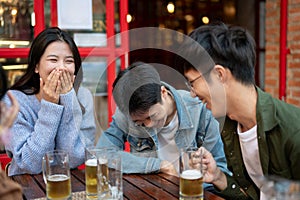 Group of happy friends are enjoying talking and drinking beers while hanging out at a restaurant