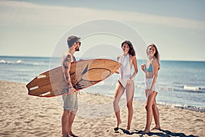 Group of happy friends going to surf at the beach Sporty people