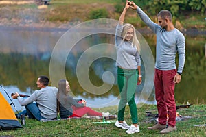 Group of happy friends with guitar, having fun outdoor, near bonfire and tourist tent. Camping fun happy family