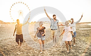 Group of happy friends having fun on the beach at sunset