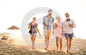 Group of happy friends having fun at seaside sunset - Summer vacations and friendship concept with young people millennials