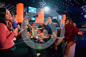 Group of happy friends are having fun, singing in karaoke club