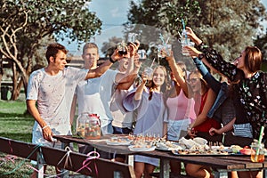 Group of happy friends having fun together celebrating a birthday at the outdoor park. Joyful friends cheering with