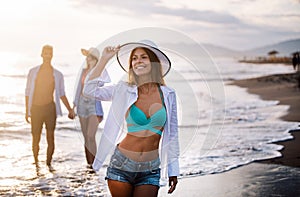 Group of happy friends having fun walking down the beach at sunset