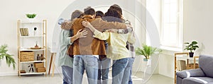 Group of happy friends hugging indoors and enjoying spending time together.