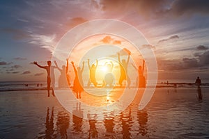 Group of happy friends jumping on beach against sunset