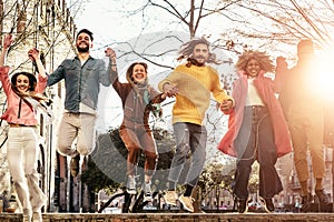 Group of happy friends jumping outdoor - Millennial young people having fun dancing and celebrating at sunset outside