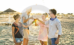 Group of happy friends millennial having fun at beach party drinking fancy cocktails at sunset - Summer joy and friendship