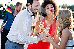 Group of happy friends partying and toasting drinks