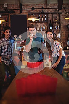 Group of happy friends playing beer pong game