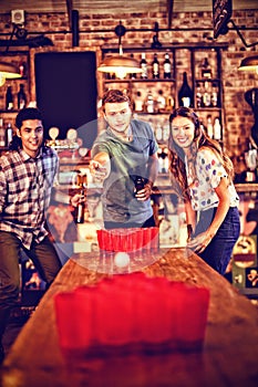 Group of happy friends playing beer pong game