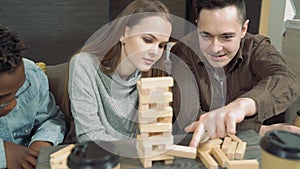 Group of happy friends playing block removal game and giving five in the living room