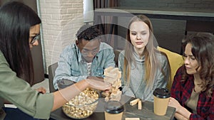 Group of happy friends playing block removal game at home