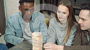 Group of happy friends playing block removal game in the living room.