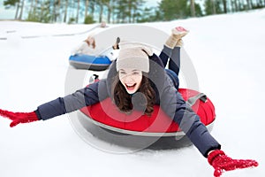 Group of happy friends sliding down on snow tubes