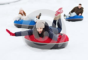 Group of happy friends sliding down on snow tubes