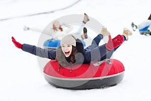 Group of happy friends sliding down on snow tubes