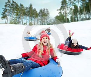 Group of happy friends sliding down on snow tubes