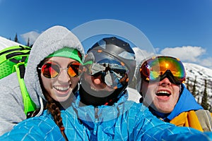 Group of happy friends snowboarding doing selfie