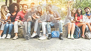 Group of happy friends using smartphones for taking photos and watching videos - Teenagers having fun outdoor with technology