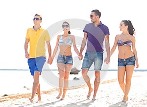 Group of happy friends walking along beach