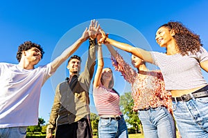 Group of happy gen z friends touching hand raised up to each other. Concept of trust in future and success in life. Diverse