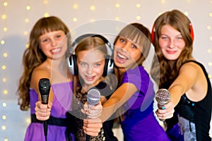 Group of happy girls singing on karaoke