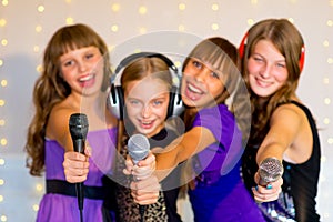 Group of happy girls singing on karaoke