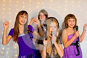 Group of happy girls singing on karaoke