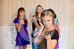 Group of happy girls singing on karaoke