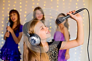 Group of happy girls singing on karaoke